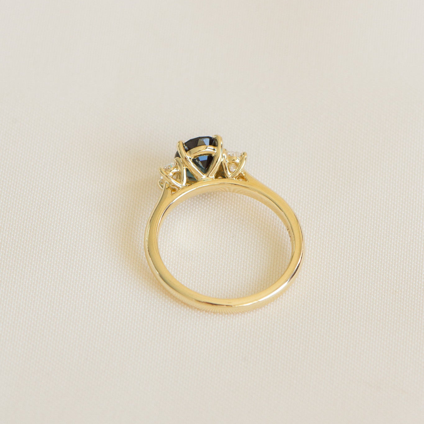 Australian blueish teal sapphire engagement ring with 1.78ct centre sapphire, 0.29ct oval lab diamonds, set in 18k yellow gold cathedral three-stone setting.
