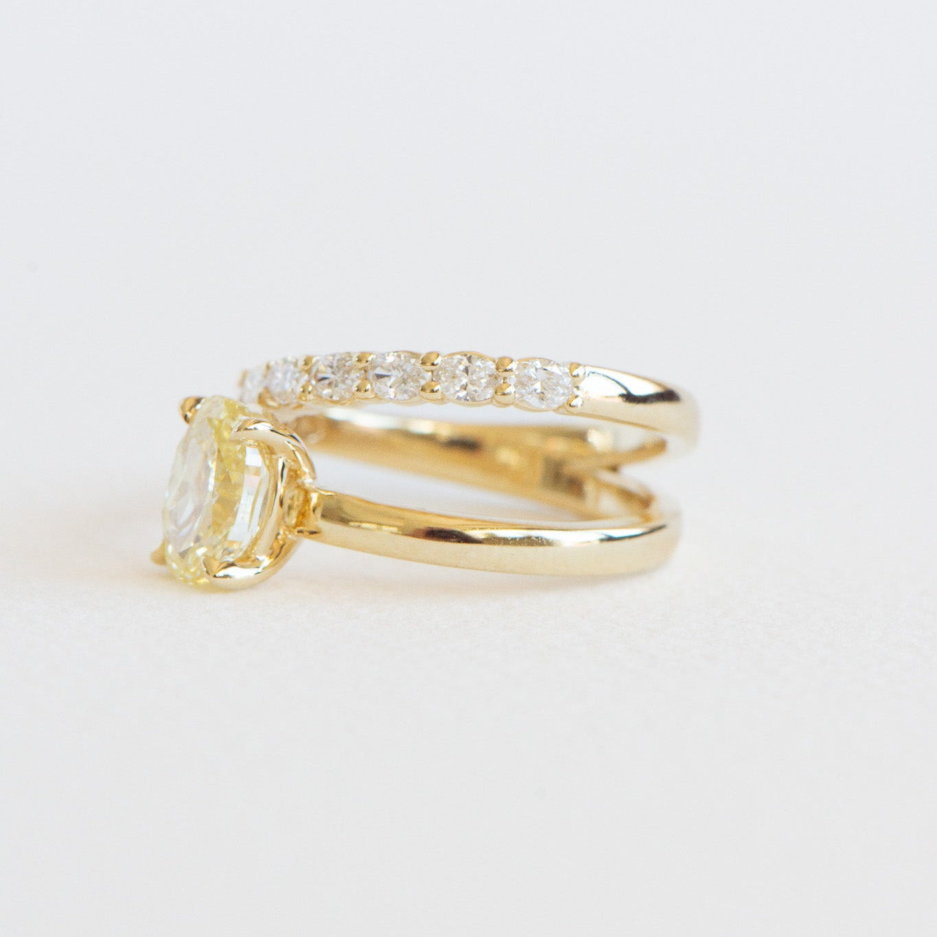 Side view of Romi yellow oval engagement ring showing accent diamonds and band detail