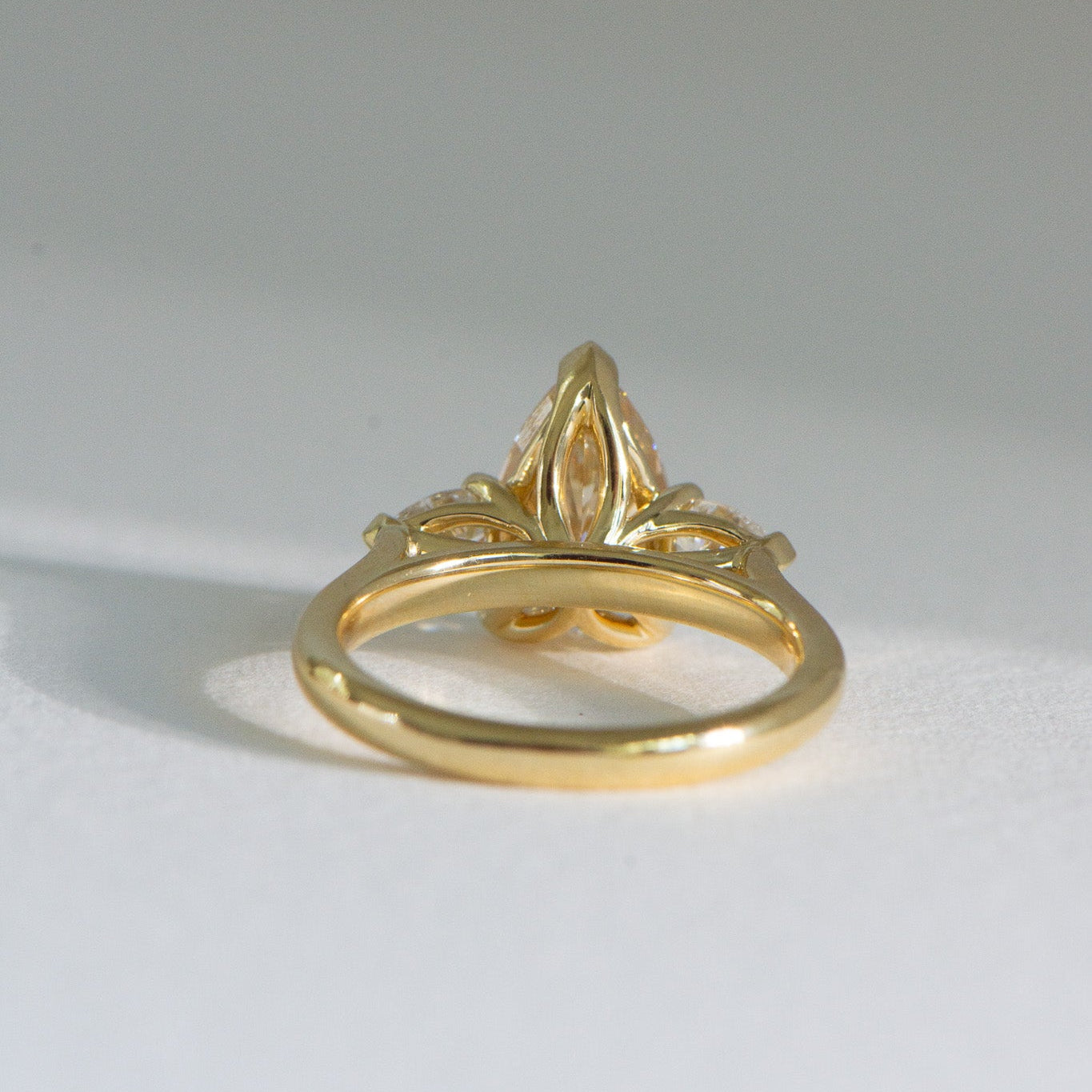 Underside Solenne 3ct fancy yellow pear lab grown three stone diamond engagement ring in 18k yellow gold, handcrafted by Matthews Jewellers